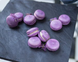 Obraz na płótnie Canvas purple and white filled macaroon dessert on grey stone serving platter board
