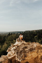 A couple in love  sits on the big stone with a breathtaking mountains view on the background.  Copy space.