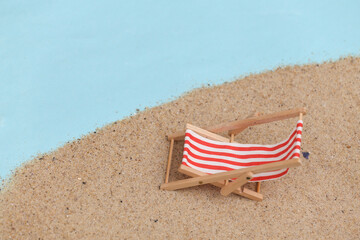 Fototapeta na wymiar Summer beach travel vacation concept. Mini beach deck chair on sand