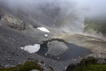 Alpine lake in a rocky valley. Valley in front of the Koshtan pass (3450 meters above sea level). Caucasus, Russia.