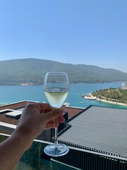 Obraz premium Bodrum, Turkey - August, 2020: Collection champagne MOET in a glass with bubbles in hand against the emerald Aegean Sea background. Happy lifestyle