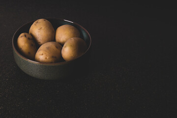 potatoes in a dark green bowl on black stone surface