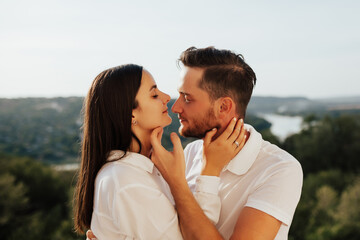 Close up side view portrait of a wonderful couple embracing closely with closed eyes smiling while dating. Young couple in love outdoor.