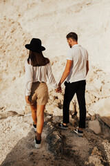 Stylish couple on the background of a amazing rocky mountain. Young couple walk holding hands along the rocky mountain.