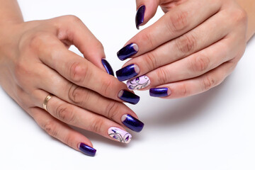 Gel manicure with flowers. Blue shiny, purple shiny moon manicure on long square nails close-up on...