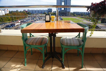 Cafe interior. Open terrace. Table with chairs against the background of the city. Interior design. Restaurant reservations. Wooden furniture. Street diner. Food on the air. Interior for advertisin