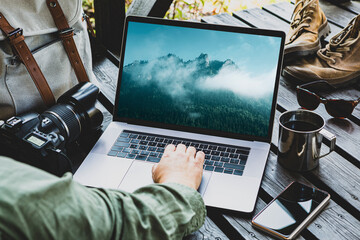Traveler or travel photographer working on laptop among his equipment