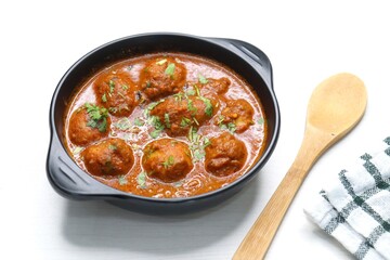 Indian cuisine - Kashmiri Dum Aloo or Potatoes in red gravy over white background. Garnished with coriander. Serve hot with rice or Naan/roti. Copy space. Panjabi Dam alu curry.