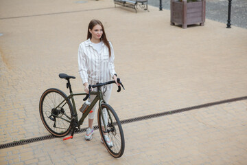 Top view shot of a stylish woman standing near her bicycle outdoors in the city, copy space