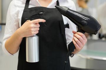 Hairdresser with hair dryer and spray