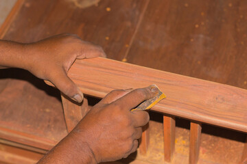 A carpenter woodworking by hand. Making the wood surface smooth with sand paper.
