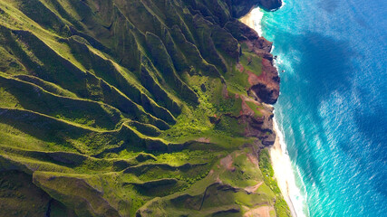 Aerial Na Pali Coast, Kauai Hawaii. These emerald-hued cliffs with razor-sharp ridges tower above the Pacific Ocean, revealing beautiful beaches and waterfalls that plummet to the lush valley floor. 