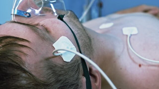 Male Patient Breathing Oxygen Support In Hospital, Next To Heart Rate Machine.