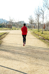 Rear view of a fitness girl training running in the morning park