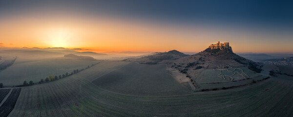 Spis Zipser Castle above valley at sunrise in fog with celtic horse symbol