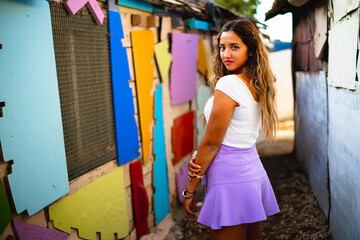 Shallow focus of a female wearing a purple skirt and posing in an alley of old colorful buildings