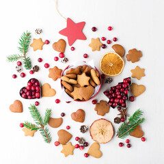Christmas Decorative Border made of Festive Elements, gingerbread cookies, cranberries on white wooden background.