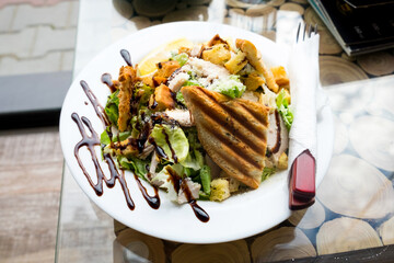 Caesar salad with roasted chicken breast, parmesan cheese, lettuce leaf, cherry tomatoes, cheese sauce and toasted bread