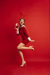 Stylish dancing with gift. Concept of Christmas, 2021 New Year's, winter mood, holidays. Copyspace for ad, postcard. Beautiful caucasian woman with long hair like Santa's Reindeer catching giftbox.