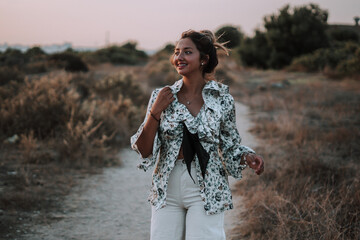 Shallow focus of a female with her hair in a messy bun walking through a field in the evening