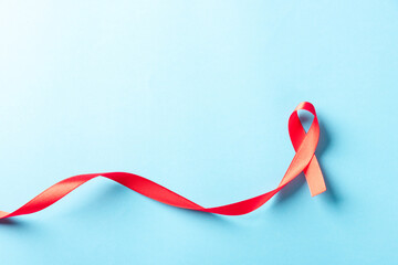Red bow ribbon symbol HIV, AIDS cancer awareness with shadows, studio shot isolated on blue background, Healthcare medicine concept, World AIDS Day