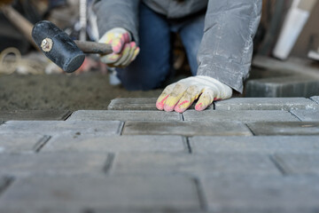 Man laying paving stones on the floor using a rubber mallet