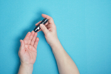 woman hand using a lancet on her finger to check blood sugar using a glucose meter,, diabetes, glycemia, healthcare concept.