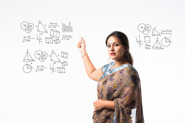 Portrait of asian Indian lady teacher in saree stands against writing board conducting online class