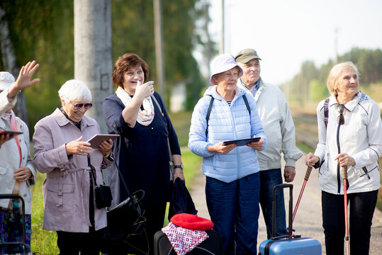 Group of positive senior elderly people looking at tablet on traveling journey during pandemic.COVID-19 travel in the New Normal.