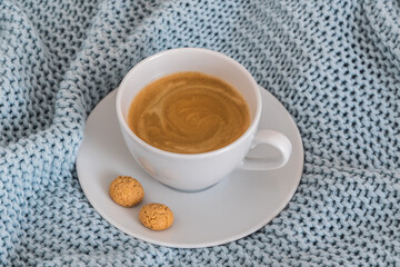 Cup of coffee on a light blue knitted wool blanket. Cozy atmosphere. Coffee break, stay at home concept.