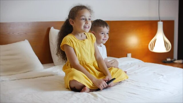 Portrait ute Little Kids While Watching TV on Laptop. Boy and Girl Watch Cartoon on Laptop on Living Room. Concept Video Game, Entertainment, Emotions, Family. Children Brother and Sister Watching TV