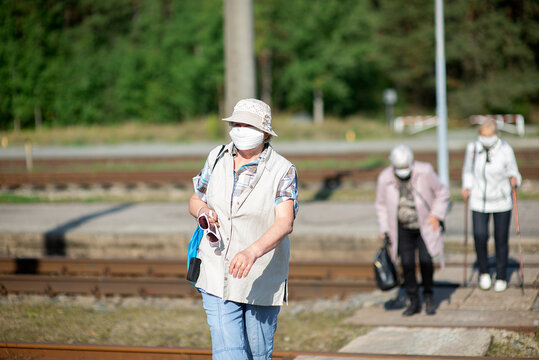 a group of senior women elderly travelers with masks on their faces cross the railway tracks