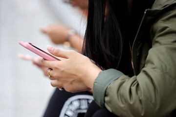 People use smartphones on a city street. Mobile phone in female hands close up, concept of online addiction, sms, social media and communication