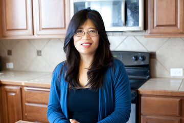 Beautiful Asian woman in early forties standing in kitchen