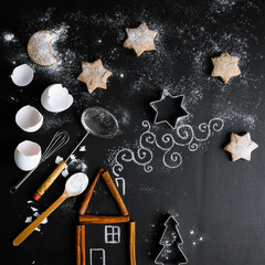 Cinnamon house on the table is complemented by a chalk pattern and utensils for making cookies.