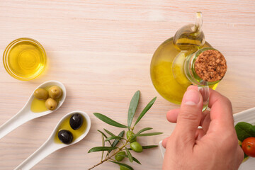 variety of olives and hand catching oil dispenser top view