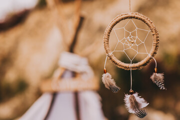 Close up of dream catcher on blurred background in evening sun light in vintage colors.