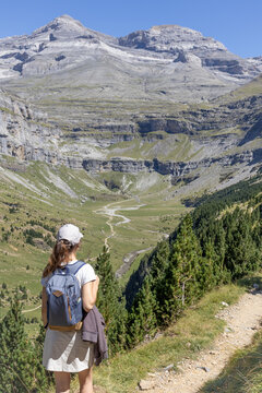 Tourist girl hiking in Cirque de Soaso with Monte Perdido and Soum de Ramond view (left to right) in Ordesa y Monte Perdido National Park. Huesca, Aragon, Spain.