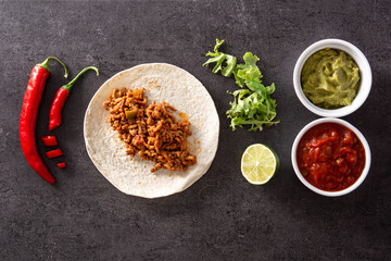 Mexican tacos ingredients on black stone.Top view