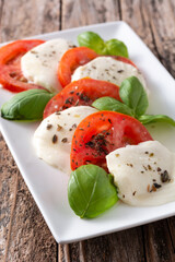 Traditional caprese salad with tomato and mozzarella cheese on rustic wooden table	