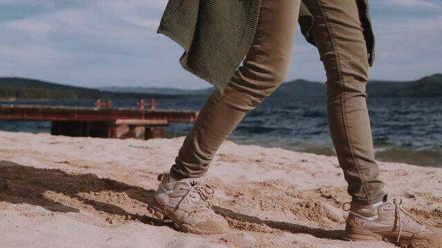 the girl walks along the beach on the shore, indifferently kicks the sand with her feet