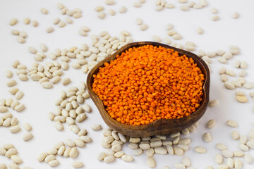 Raw,Dry Red Lentil in a wooden shape bowl on white with white beans.