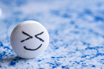 Big white cute Pill with drawn face smile on color background. the concept of antidepressants