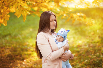 portraits of mom and baby in autumn park, mom hugs baby