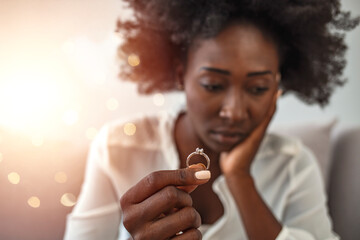 Upset depressed young woman holding wedding ring indoors, breaking off engagement, ending...