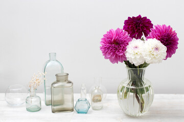 Bouquet of purple and white autumn dahlias in vase on white background.