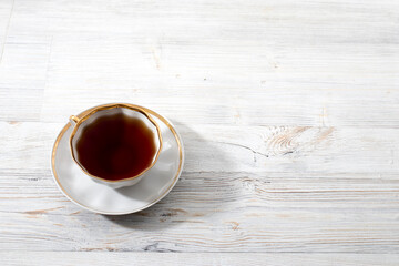 A porcelain cup with tea on long empty table. Space for text.