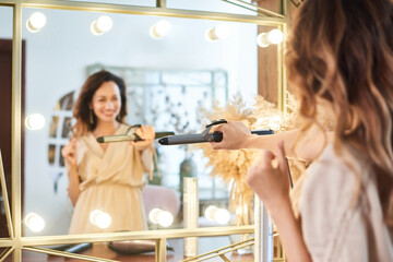 Hairdresser woman curls hair. Fashion and beauty concept. Selected focus on hands