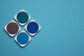 Palette of blue, turquoise and gray shades of watercolor paints on a light blue background
