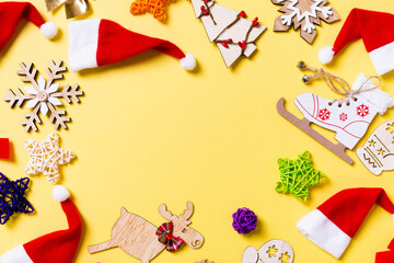 Top view of Christmas decorations and Santa hats on yellow background. Happy holiday concept with copy space